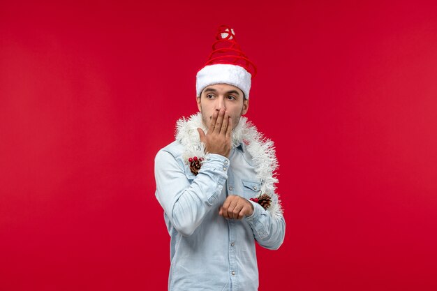 Front view of young man with surprised expression on red wall