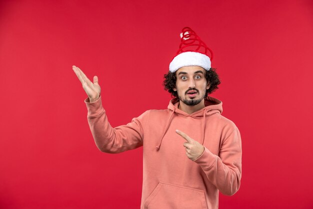 Front view of young man with surprised expression on a red wall