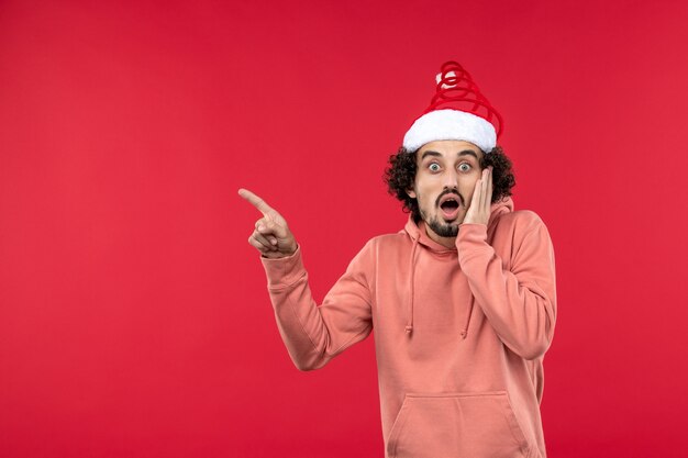 Front view of young man with surprised expression on red wall