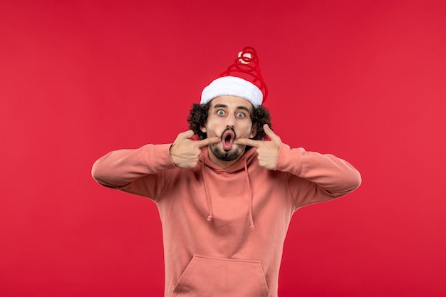 Front view of young man with surprised expression on red wall