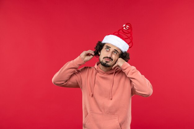 Front view of young man with thinking expression on red wall