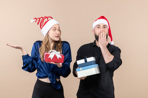 Front view of young man with woman holding presents on a pink wall