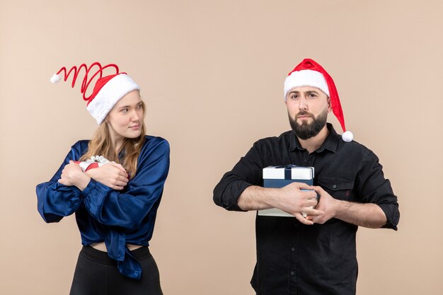 Front view of young man with woman holding presents on a pink wall