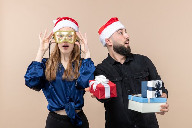 Front view of young man with woman holding presents on a pink wall