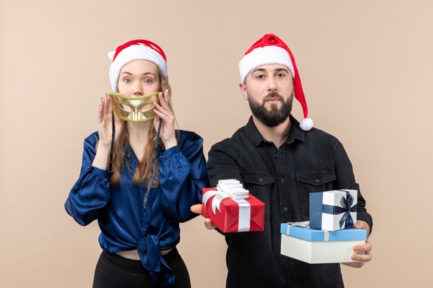 Front view of young man with woman holding presents on pink wall