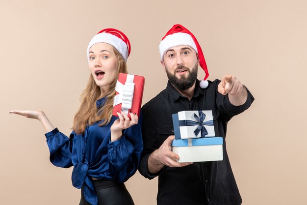 Front view of young man with woman holding presents on pink wall