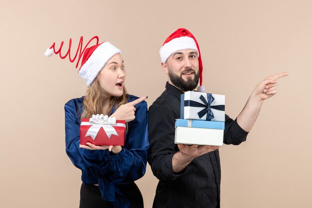 Front view of young man with woman holding presents on pink wall