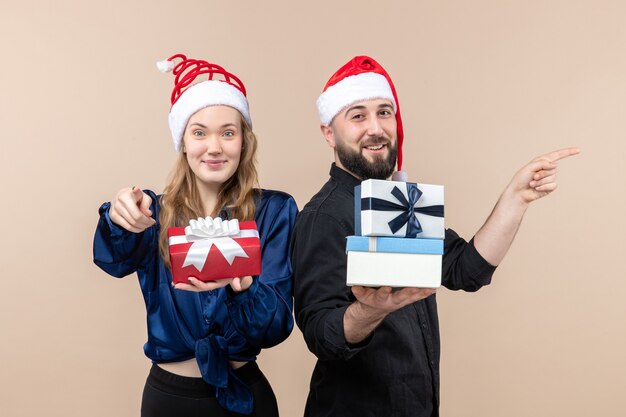 Front view of young man with woman holding presents on pink wall