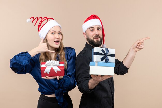 Front view of young man with woman holding presents on pink wall