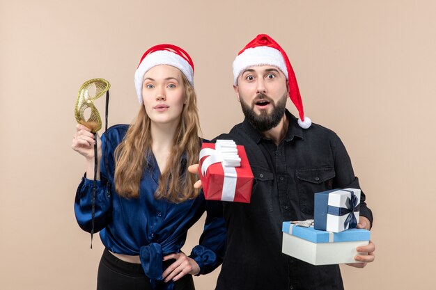 Front view of young man with woman holding presents on pink wall