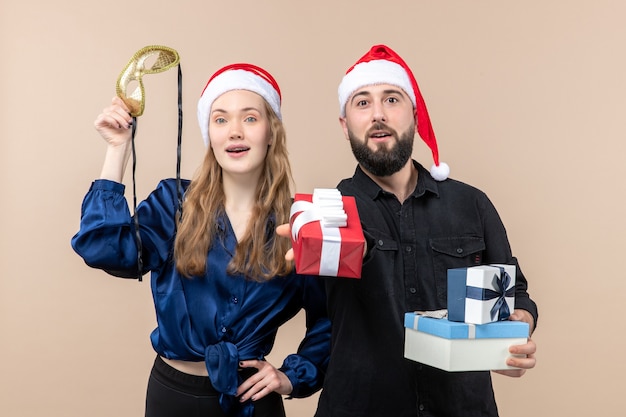 Front view of young man with woman holding presents on the pink wall