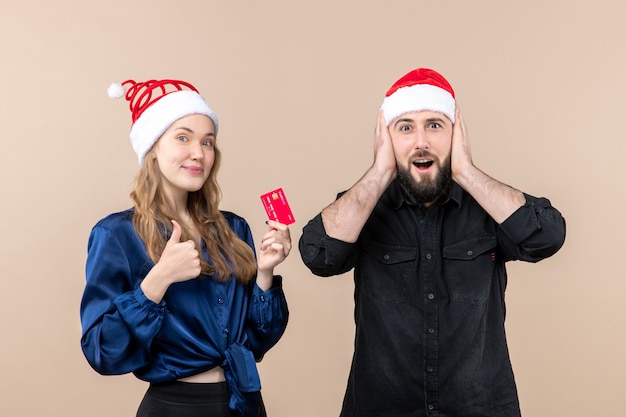 Front view of young man with woman who's holding bank card on pink wall