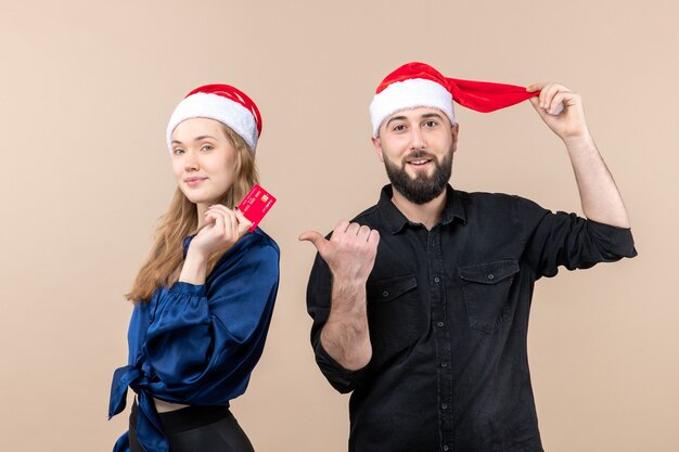 Front view of young man with woman who's holding bank card on pink wall