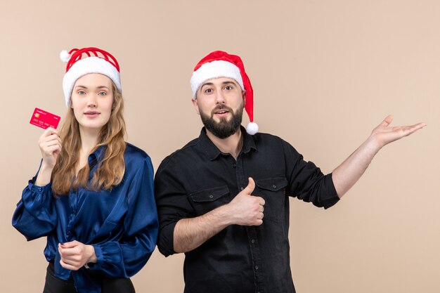 Front view of young man with woman who's holding bank card on pink wall