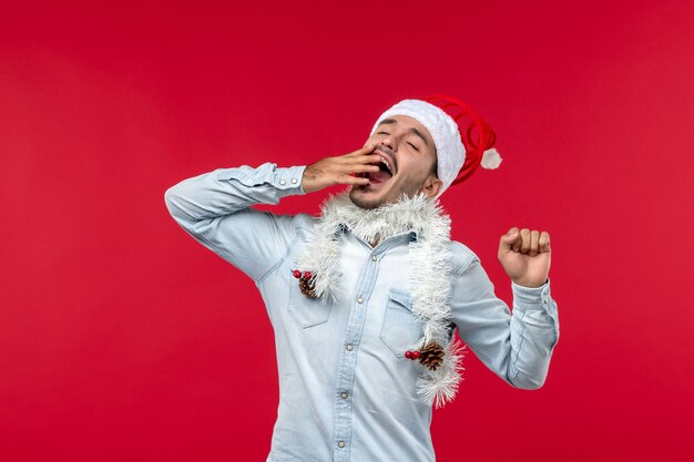 Front view of young man yawning on red wall