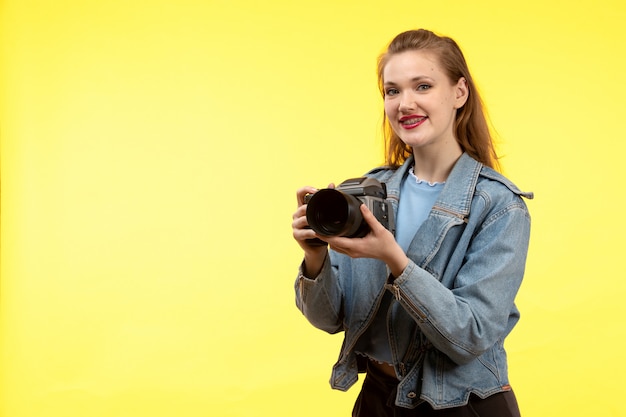 파란색 셔츠 검은 바지와 진 코트 포즈 사진 카메라를 들고 웃고 행복 한 전면보기 젊은 현대 여성