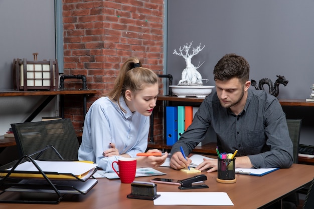 Вид спереди молодой мотивированной и трудолюбивой офисной команды, сосредоточенной на одной проблеме в офисной среде