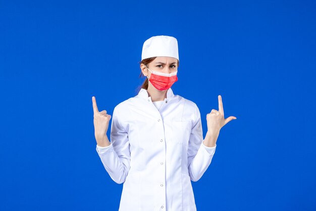 青い壁に赤い保護マスクと医療スーツの正面図若い看護師