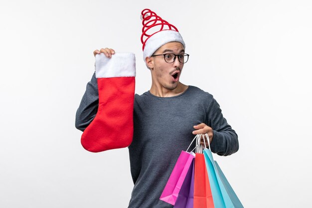 Front view of young person after holiday shopping on white wall