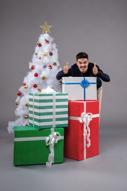 Front view young person with christmas presents on grey 
