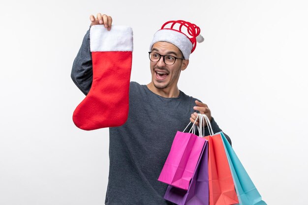 Front view of young person with packages and sock on white wall