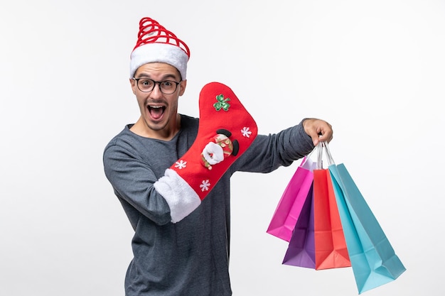 Front view of young person with packages and sock on white wall