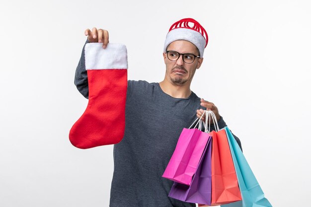 Front view of young person with packages and sock on white wall