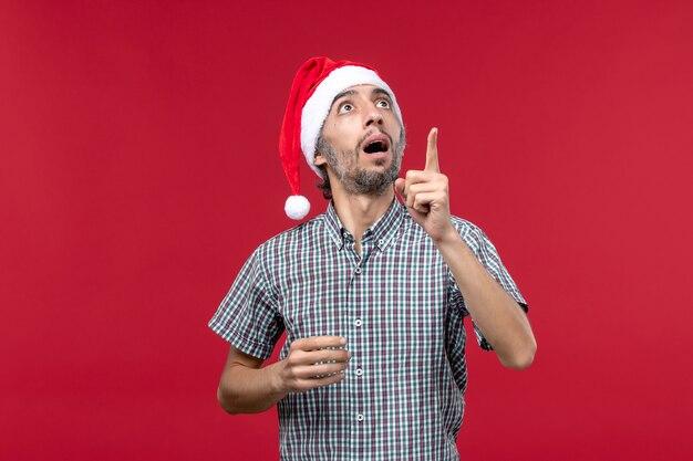 Front view young person with surprised expression on red wall red new year male holiday