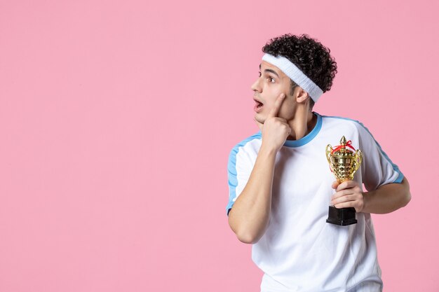 Front view young player in sport clothes with golden cup on pink wall