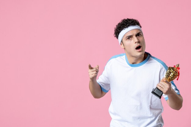 Front view young player in sport clothes with golden cup on pink wall