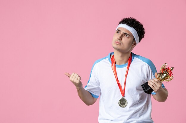 Front view young player in sport clothes with golden cup on pink wall