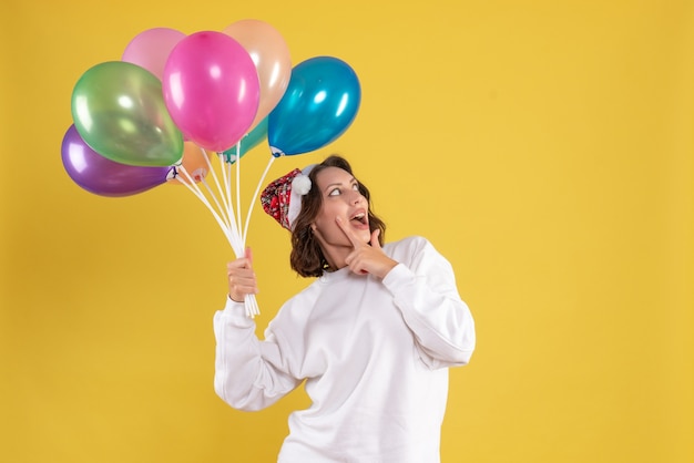 Free photo front view young pretty female holding balloons on the yellow christmas woman new year color emotion