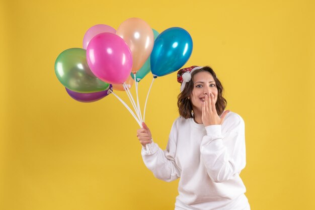 Front view young pretty female holding balloons on yellow new year emotions christmas color woman