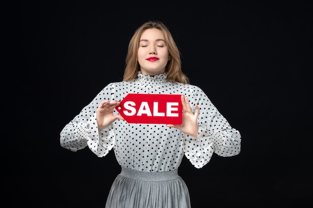 Free photo front view young pretty female holding red sale writing on black wall color shopping fashion photo emotion