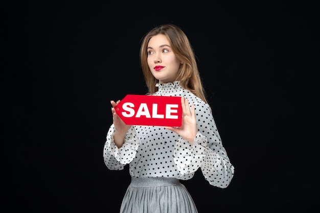 Front view young pretty female holding red sale writing on black wall shopping fashion photo woman emotion