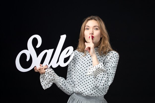 Front view young pretty female holding sale writing on the black wall color shopping beauty model fashion photo emotion