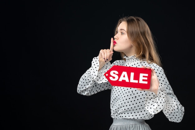 Front view young pretty female holding sale writing on black wall color shopping fashion photo woman emotions red