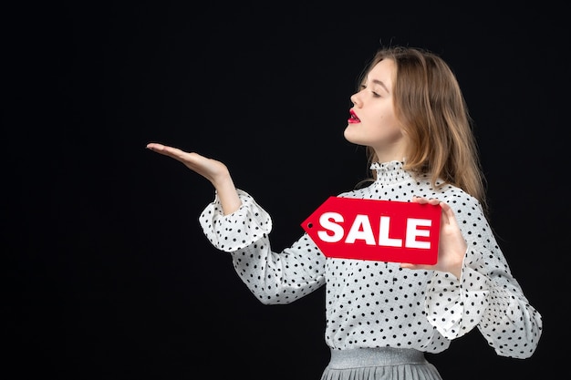 Free photo front view young pretty female holding sale writing on a black wall color shopping photo woman emotion red fashion