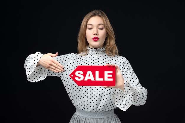 Front view young pretty female holding sale writing on a black wall model beauty emotion shopping fashion woman color red