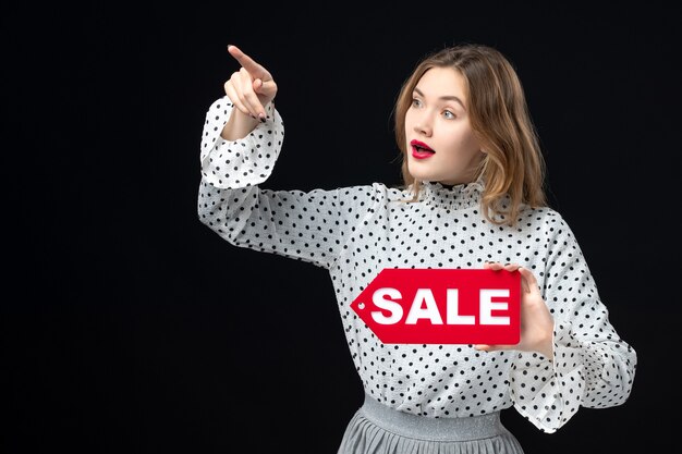 Front view young pretty female holding sale writing on a black wall model beauty emotion shopping fashion woman color