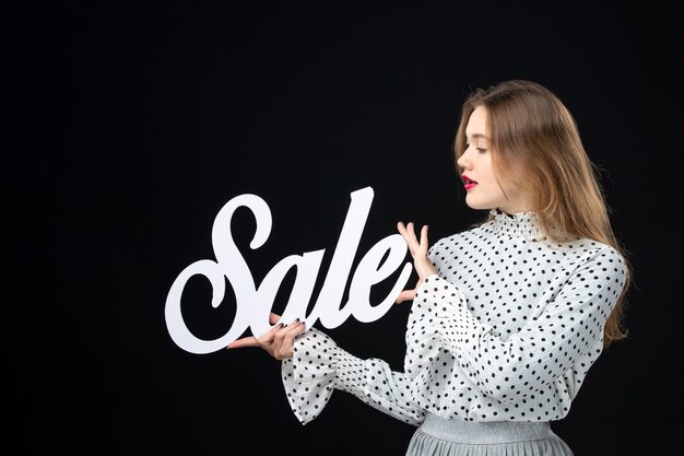 Front view young pretty female holding sale writing on a black wall model shopping beauty fashion emotion color