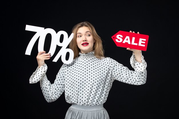 Front view young pretty female holding sale writing and on black wall