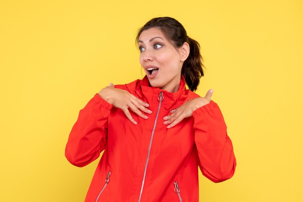 Front view young pretty female in red coat on yellow background