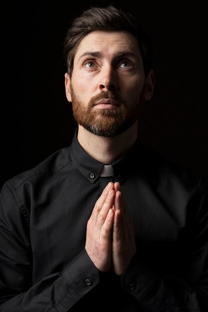 Front view young priest praying indoors