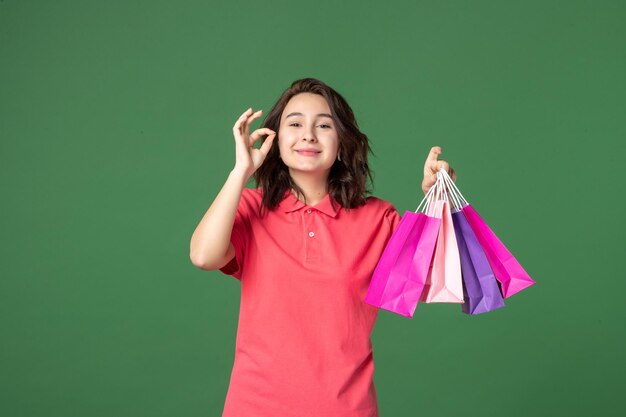 Front view young saleswoman holding gift packages on green background job worker boutique sale present shopping uniform emotion