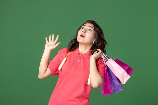 Front view young saleswoman holding gift packages on green surface