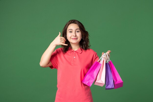 Front view young saleswoman holding little packages on green background job color shopping presents worker boutique sale