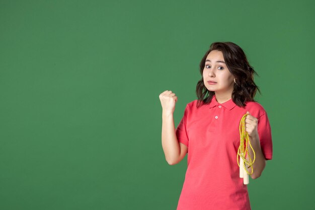 Front view young saleswoman holding skipping rope on green surface