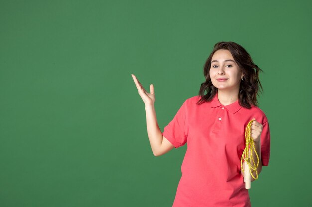 Front view young saleswoman holding skipping rope on green surface