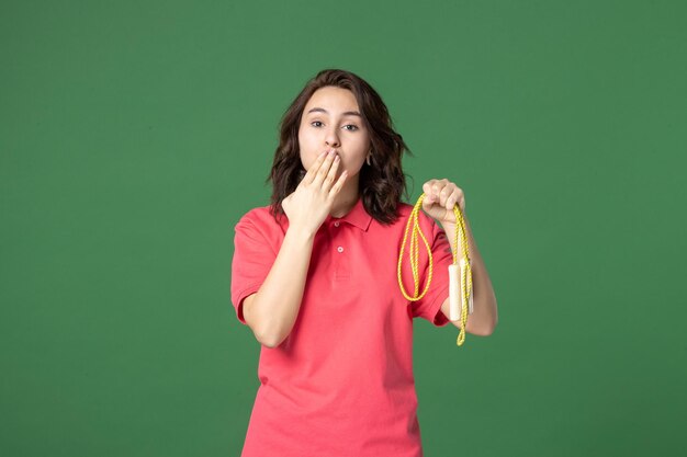 Front view young saleswoman holding skipping rope and sending kisses on green background sale boutique uniform shopping worker sport health job present